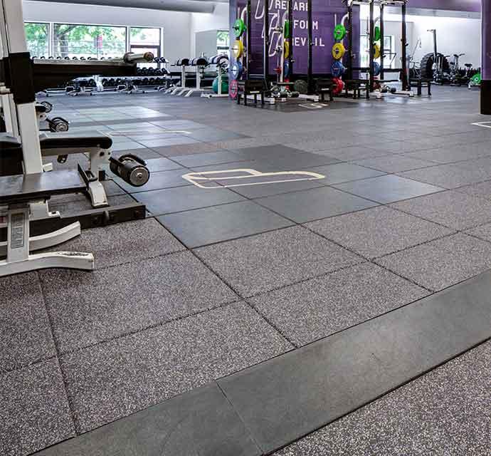 Spacious gym with weightlifting equipment and designated floor zones for diverse fitness activities.