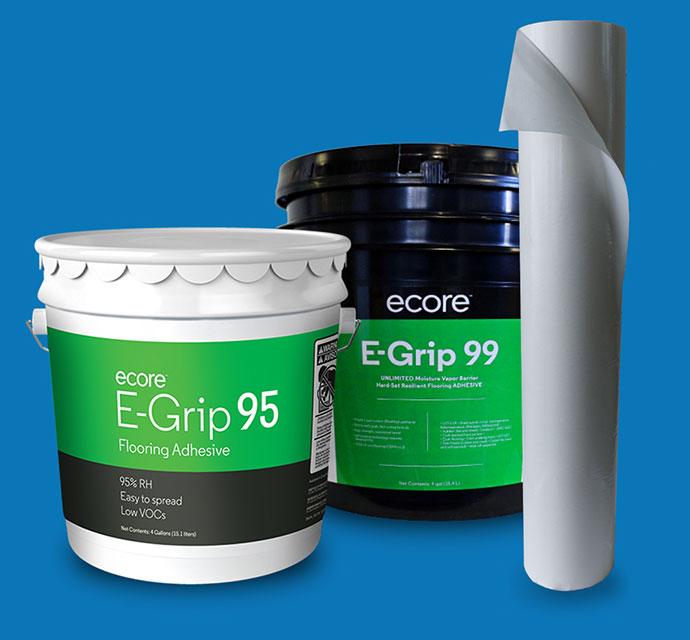 Two buckets of Ecore E-Grip flooring adhesive and a roll of flooring material on a blue background.