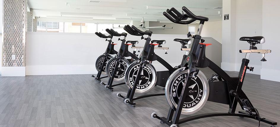 A few spin bikes in a line on a gray studio floor. 