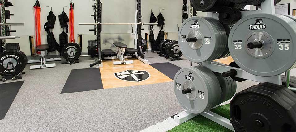 Well-equipped gym with weights and fitness equipment on a grey floor with custom logos.
