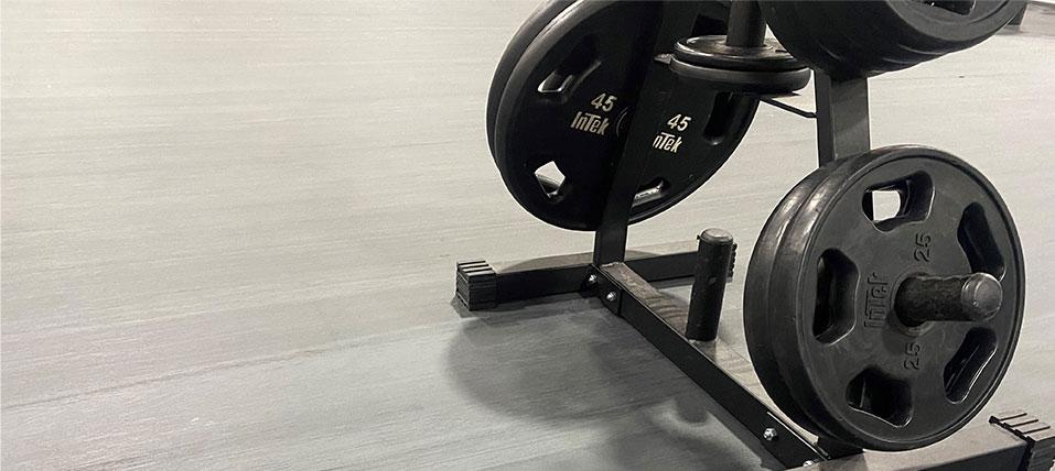 Close-up of barbell plates stacked on a rack on a Moxie Collection floor.
