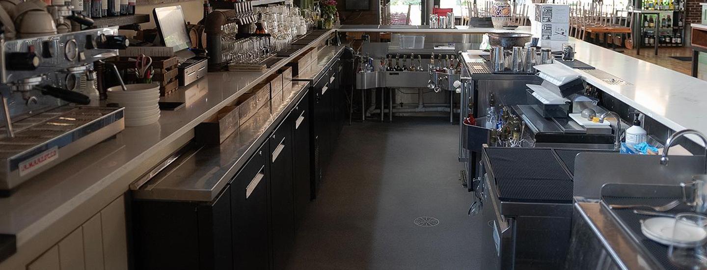 Spacious bar interior with espresso machines, taps, and seating area in the background.